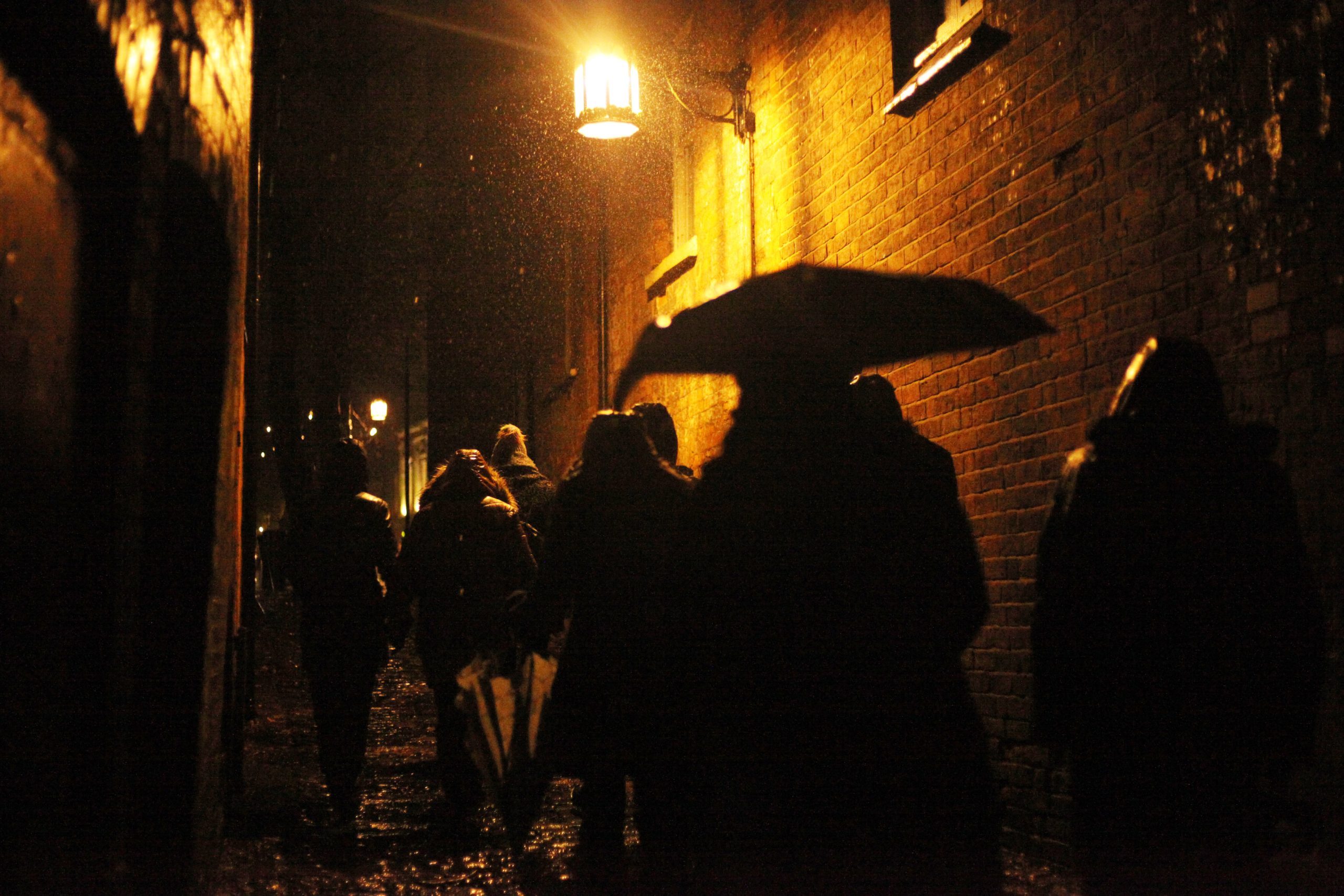 audience walking up a narrow cobblestone pathway at nighttime