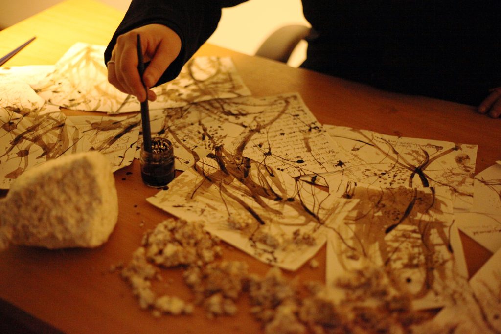 closeup of artist drawing and painting with mushroom ink