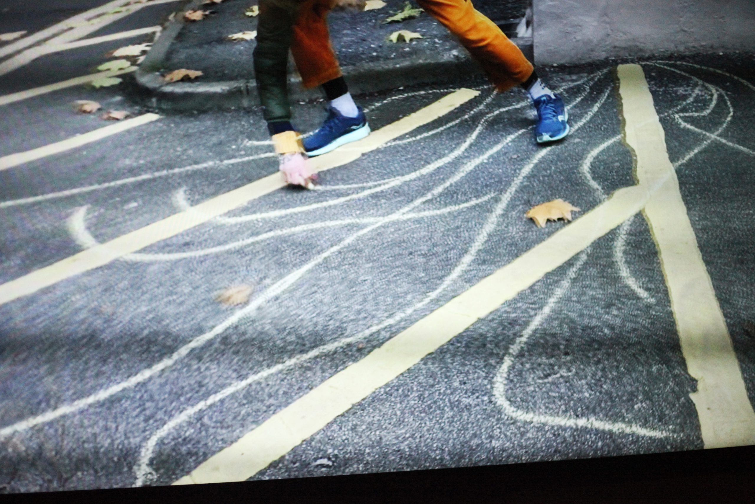 person drawing in chalk on the road
