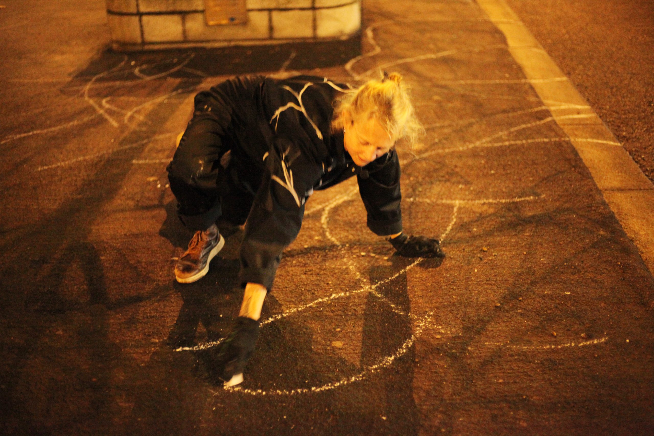 person drawing in chalk on pavement at nighttime